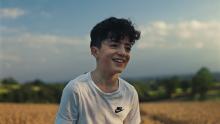 A young boy smiles at a sunset off camera 