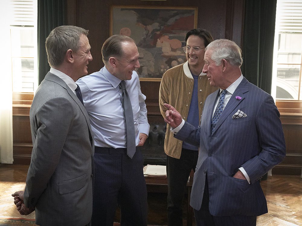 Actors Daniel Craig and Ralph Fiennes talk to Prince Charles, alongside director Cary Joji Fukunaga